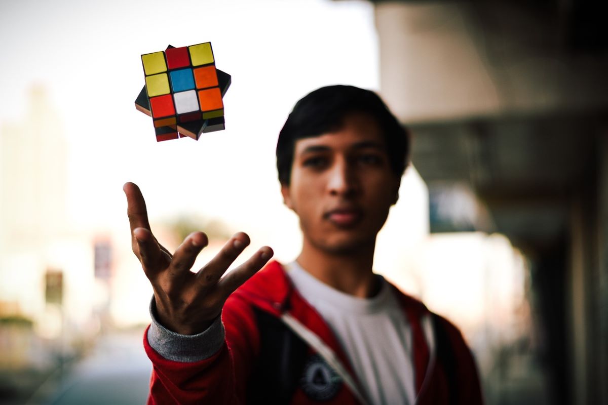 Picture of young man tossing a cube puzzle for adults in the air