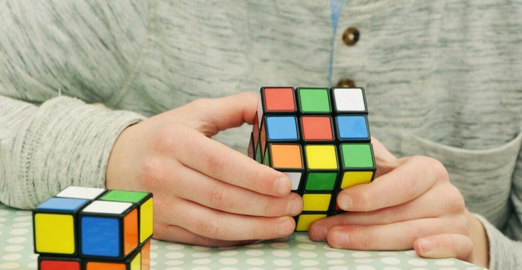 Picture of male's hands only that is solving a cube puzzle for adults