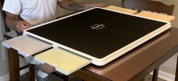 Person sitting at a plastic jigsaw puzzles tables with 4 drawers