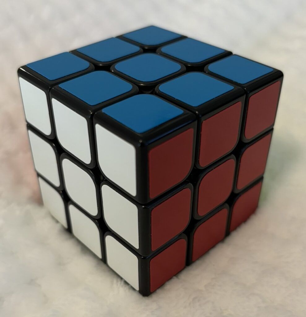 Solved 3x3 Rubik's cube with blue, white and red sides showing.