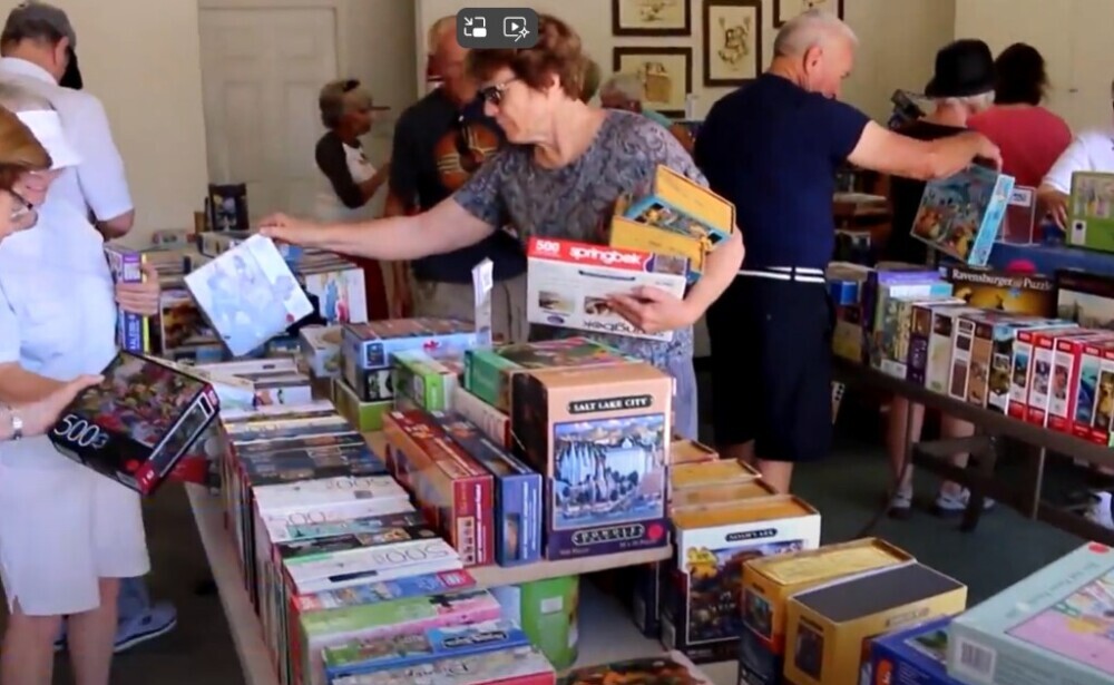 Picture of several people looking at puzzles in a used jigsaw puzzle swap meet