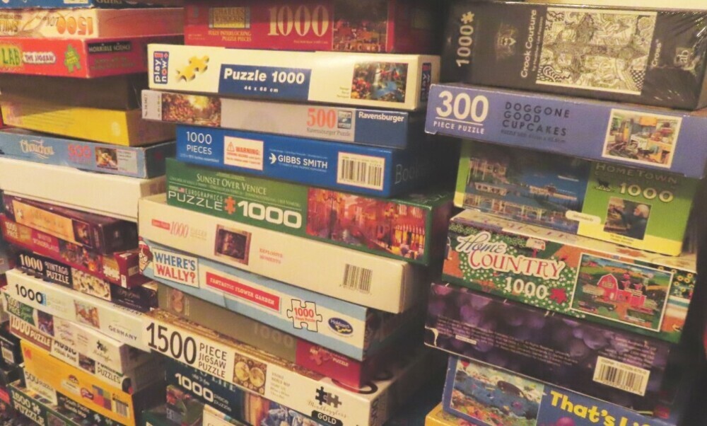 Three stacks of various used jigsaw puzzles